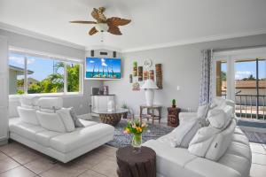 a living room with white furniture and a ceiling fan at Paradise PalmsDockPoolKayaks GrillView! in Marathon