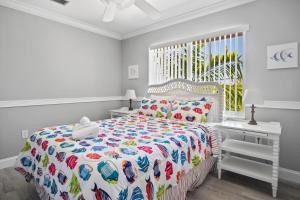 a white bedroom with a bed with a colorful comforter at Paradise PalmsDockPoolKayaks GrillView! in Marathon +72 photos