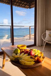 a plate of fruit on a table with a view of the ocean at Apartamento no Falesias de Pipa - Veleiros 212 in Pipa
