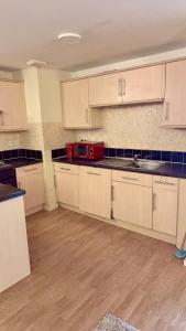 a kitchen with white cabinets and a red microwave at 2 Spacious Double Bedroom Apartment - Bradford in Bradford