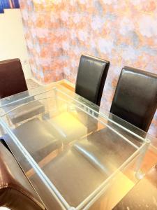 a glass table with three leather chairs around it at 2 Spacious Double Bedroom Apartment - Bradford in Bradford