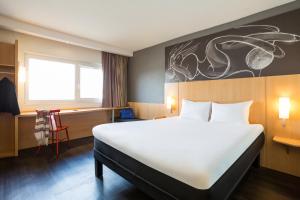 a bedroom with a large white bed and a desk at ibis Bordeaux Lac in Bordeaux