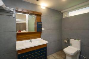 a bathroom with a sink and a toilet and a mirror at Akanta Cherai Beach Resort in Cochin