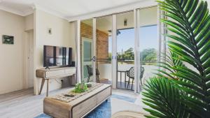 a living room with a sink and a desk and a plant at Priority Beach Stay in Coffs Harbour