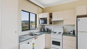 a kitchen with white appliances and a window at Priority Beach Stay in Coffs Harbour
