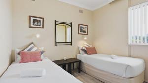 a bedroom with two beds and a mirror on the wall at Priority Beach Stay in Coffs Harbour