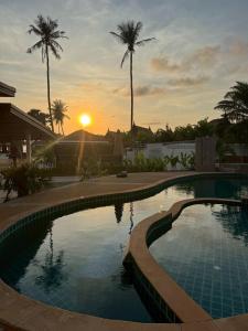a pool at sunset with palm trees in the background at Tree Space Lanta Pool Stay Quiet & Near Beach in Ko Lanta +20 photos