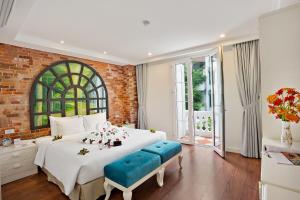 a bedroom with a large white bed and a brick wall at Hanoi La Selva Hotel in Hanoi