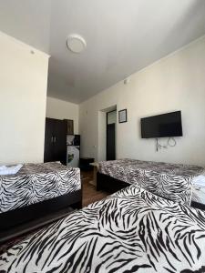 a hotel room with two beds and a flat screen tv at Inn Kochevnik in Cholpon-Ata