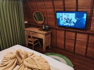a room with a tv and a bed and a table at Simbar Pertiwi Villa in Ubud