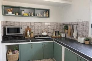 a kitchen with green cabinets and a microwave at Ardor Homestay in Jabalpur