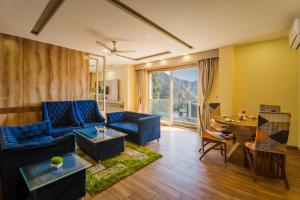 a living room with a blue couch and a table at Tripli Hotels Shivaay in Dharamshala