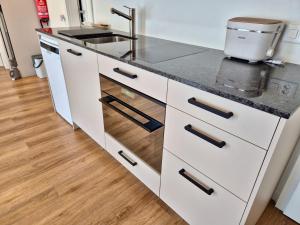 a kitchen with white cabinets and a sink at Stilvolles Wohnen an der Goldküste, nahe Zürich - 55m2 in Erlenbach