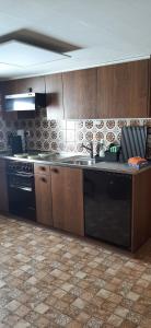 a kitchen with wooden cabinets and a black dishwasher at Ferienwohnung Toggilodge in Unterwasser +23 photos