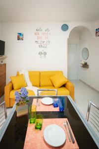 a living room with a yellow couch and a table at Dimora del Mare in Isola Bacucco