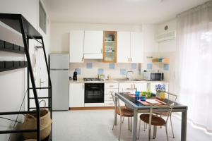 a kitchen with white cabinets and a table and chairs at Dimora del Mare in Isola Bacucco