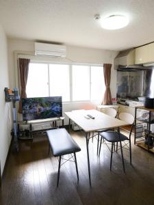 a living room with a table and chairs and a television at ROOMzero 5号室 in Hanazonomachi