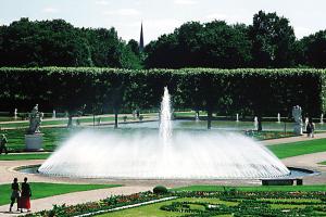 a fountain in a park with people walking around it at H+ Hotel Hannover in Hannover