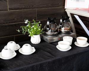 a table with cups and saucers and coffee pots at Hotel Beverly Inn Batam Center in Batam Center