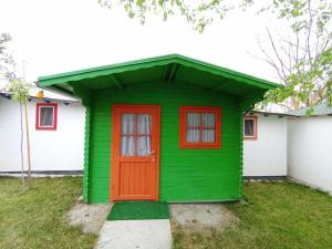 a green house with a red door in a yard at Casa Didi in Vama Veche