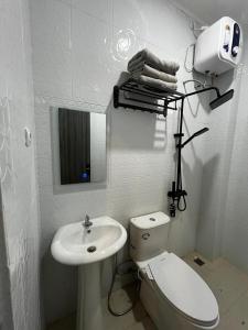 a white bathroom with a toilet and a sink at Stone Valley Resort & Beach in Tepus