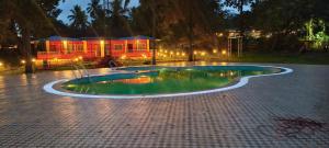 a swimming pool at night with a house in the background at Greenwoods Resort Dandeli in Kervād