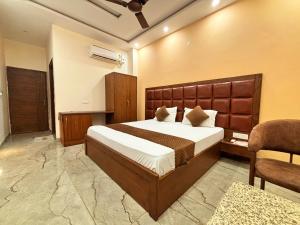 a bedroom with a large bed and a chair at HOTEL AROMA CROWN in Zirakpur