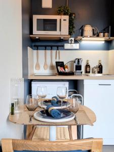 a table with wine glasses and a microwave in a kitchen at Le Solent in Courseulles-sur-Mer +15 photos