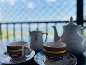 two coffee cups and a teapot on a table at Mount Vista Homestay Kandy in Kandy +28 photos