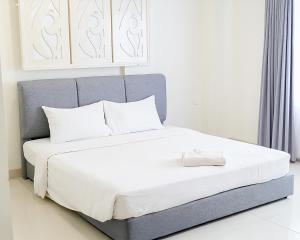 a bed with white sheets and pillows in a room at Hotel Beverly Inn Batam Center in Batam Center