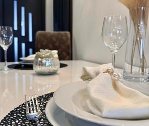 a white plate with a napkin on a table with wine glasses at Local-Lux Premium Apartment- 2 Bedrooms Balcony -2 Private Parking in Kecskemét