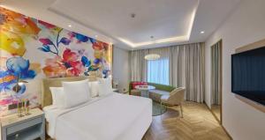 a bedroom with a white bed and a colorful wall at Hotel Royal Orchid Bangalore in Bangalore