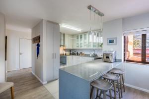 a kitchen with white cabinets and a counter with stools at Rosebud 4 Beacon Point in Mossel Bay