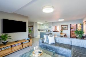 a living room with a blue couch and a flat screen tv at Rosebud 4 Beacon Point in Mossel Bay