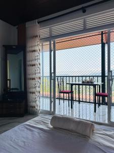 a bedroom with a bed and a balcony with a table and chairs at Mount Vista Homestay Kandy in Kandy