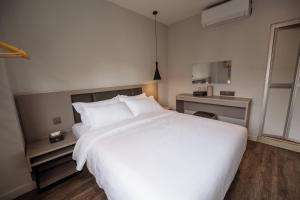 a bedroom with a large white bed and a desk at The Marion Hotel Impian Emas Branch in Skudai
