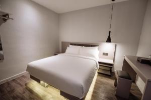a bedroom with a large white bed and a desk at The Marion Hotel Impian Emas Branch in Skudai