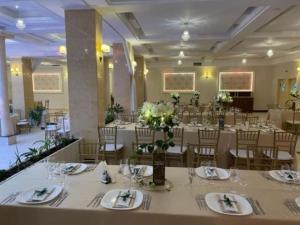 ein Festsaal mit weißen Tischen und Stühlen und Blumen in der Unterkunft Hotel Tiara in Ploieşti