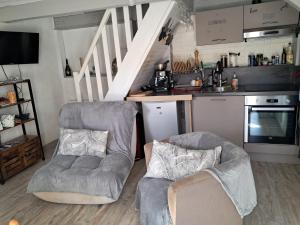 a living room with two chairs and a kitchen at La Modestine in Lanuéjols
