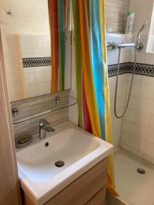 a bathroom with a sink and a rainbow shower curtain at La Modestine in Lanuéjols +8 photos