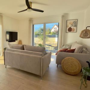 a living room with two couches and a ceiling fan at Villa Saint Mart-Tout Inclus-Plage à 7 min à pied in Saint Martin de Brehal
