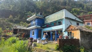 two people standing in front of a blue house at Mantra Mountain Organic Homestay in Pokhara
