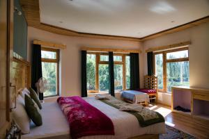 a bedroom with a large bed and large windows at Semba retreat in Hundar