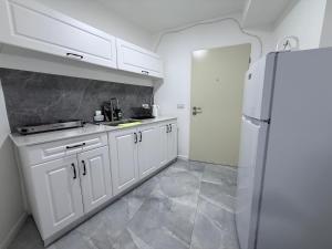 a kitchen with white cabinets and a refrigerator at Urban garden loft 3 in Haifa