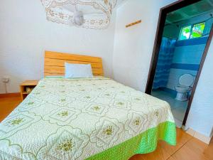 a bedroom with a bed with a green and white blanket at Musanto Hotel in Gisenyi