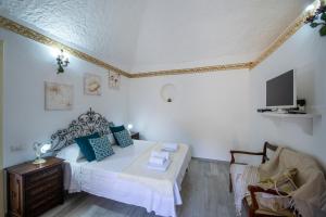a bedroom with a bed and a chair and a tv at Casa Sery in Positano