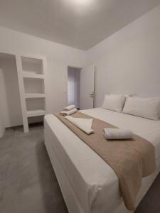 a white bedroom with a large bed with two pillows at Puerto Serifos in Livadi