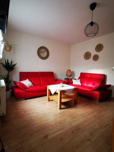 a living room with red couches and a table at Ferienwohnung Alpakahof in Kleinreinsdorf
