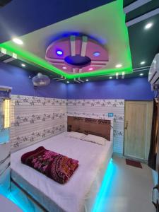 a bedroom with a large bed with a green lighting at New suvam lodge & hotel in mayapur