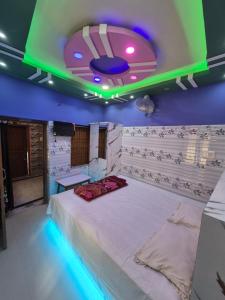 a room with a bed with a green and blue lighting at New suvam lodge & hotel in mayapur
